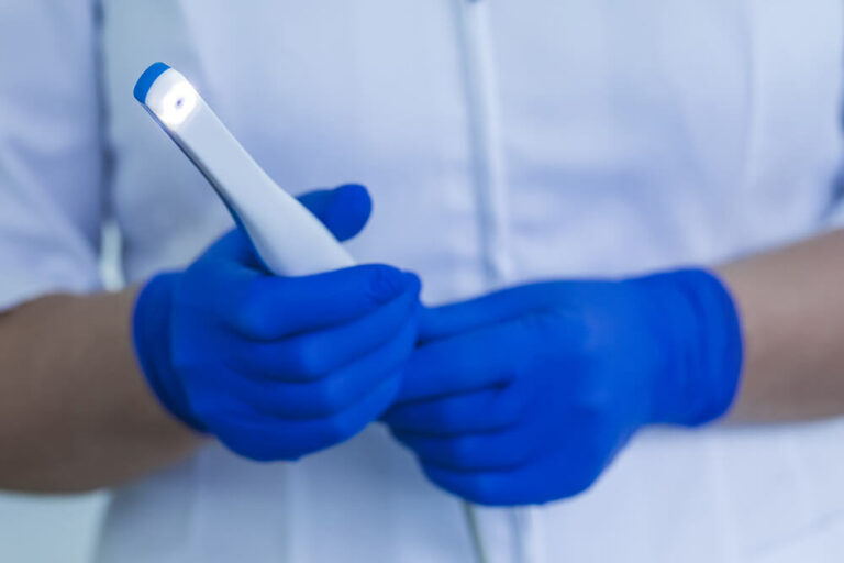 man with blue gloves holding intraoral camera